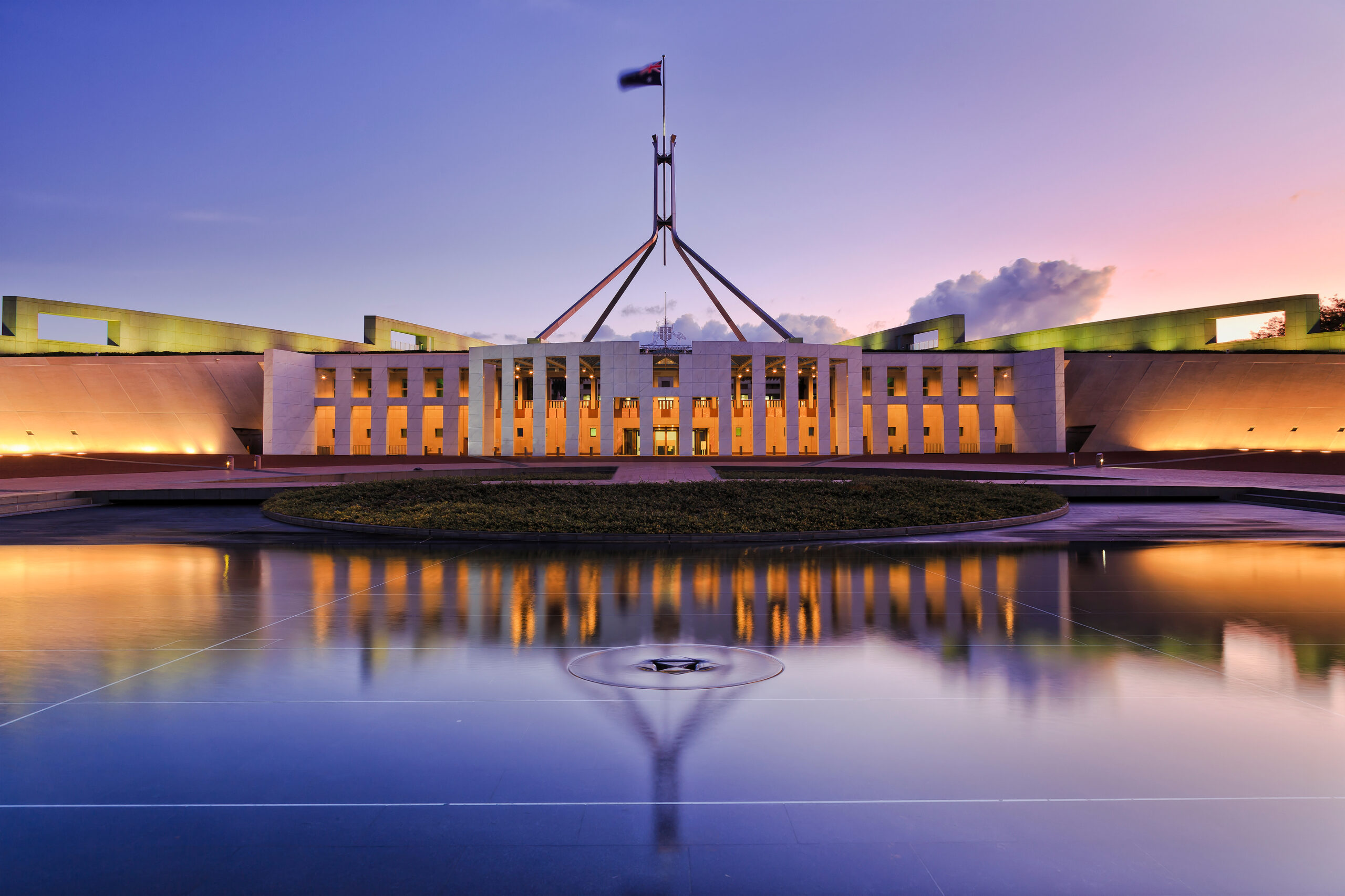 colourful reflection of Canberra's new parliament building in a fontain pond at sunset.